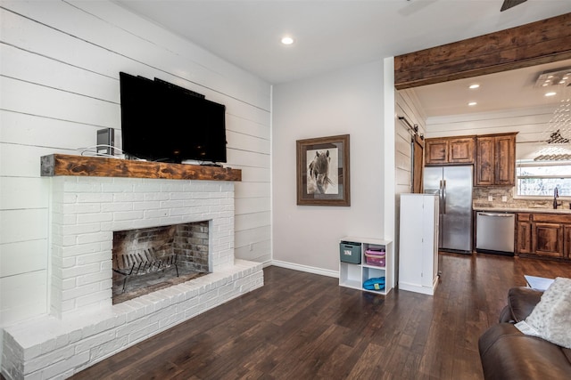 living room with a brick fireplace, sink, and dark hardwood / wood-style flooring