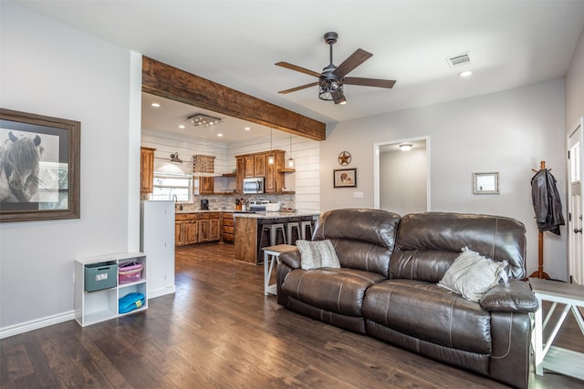 living room featuring dark hardwood / wood-style flooring, sink, beamed ceiling, and ceiling fan