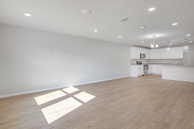 unfurnished living room featuring sink and light hardwood / wood-style floors