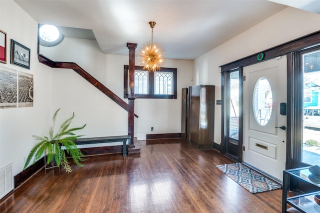 entryway with dark wood-type flooring and an inviting chandelier