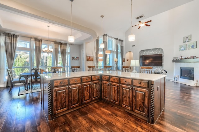 kitchen with a center island, a tile fireplace, decorative light fixtures, and ceiling fan with notable chandelier