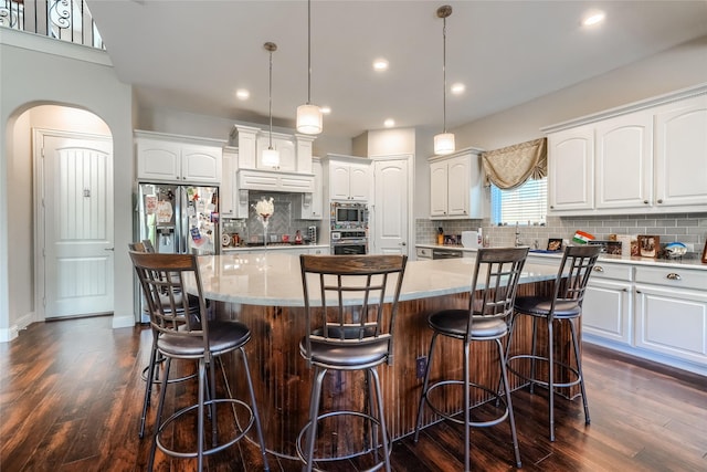 kitchen featuring pendant lighting, stainless steel appliances, decorative backsplash, a kitchen island, and white cabinets