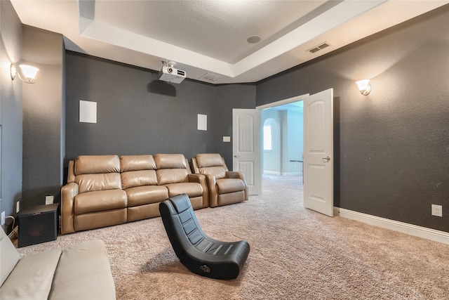 carpeted home theater with a textured ceiling and a tray ceiling