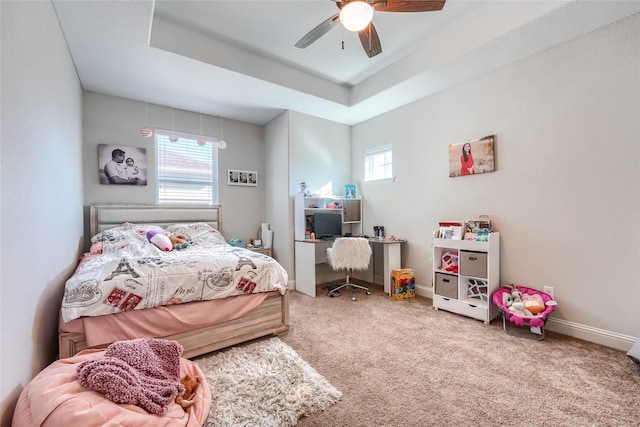 carpeted bedroom featuring a raised ceiling and ceiling fan