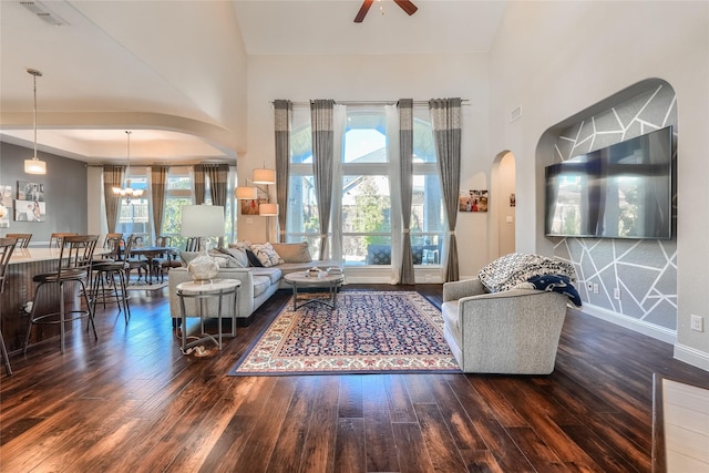 living room with dark hardwood / wood-style flooring and ceiling fan with notable chandelier