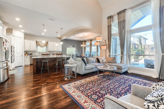 living room with a notable chandelier, dark hardwood / wood-style flooring, and plenty of natural light