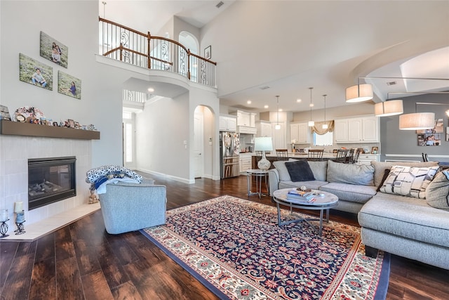 living room featuring a high ceiling, a tile fireplace, and dark hardwood / wood-style floors