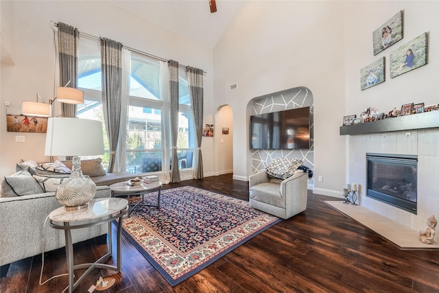 living room featuring wood-type flooring, a tile fireplace, and high vaulted ceiling