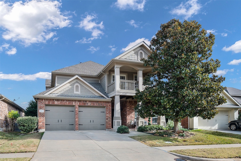 view of front facade with a garage, brick siding, driveway, and a balcony