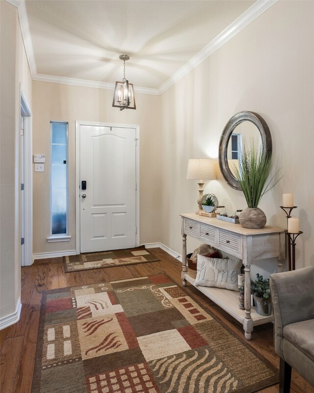 entryway featuring crown molding, dark wood-type flooring, and a notable chandelier