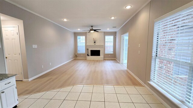 unfurnished living room featuring ornamental molding, light tile patterned floors, ceiling fan, and a fireplace