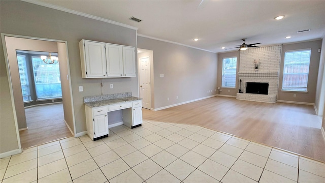 kitchen with light tile patterned floors, ornamental molding, white cabinets, and a brick fireplace