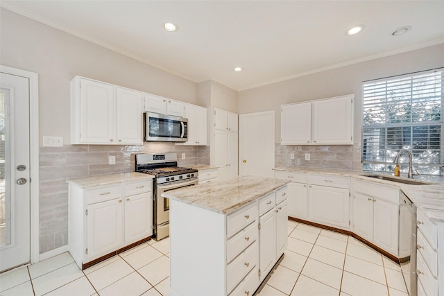 kitchen featuring light tile patterned flooring, sink, a center island, appliances with stainless steel finishes, and white cabinets