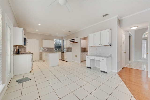 kitchen featuring white cabinets, a kitchen island, ornamental molding, and light tile patterned flooring