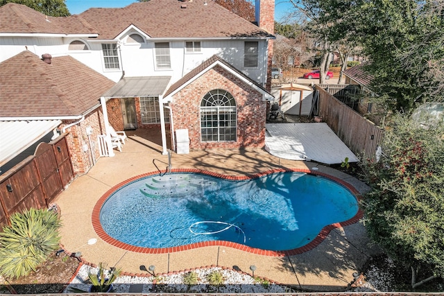 view of swimming pool featuring a patio area and a storage shed