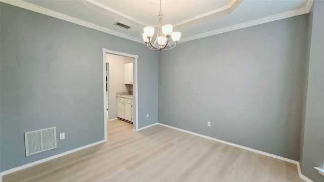 unfurnished room with a raised ceiling, ornamental molding, a chandelier, and light hardwood / wood-style flooring