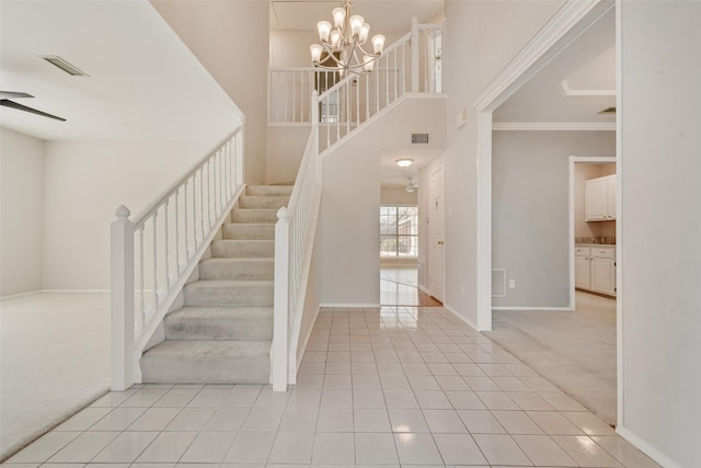 staircase with ceiling fan with notable chandelier, carpet floors, ornamental molding, and a towering ceiling