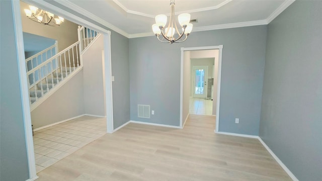 spare room featuring crown molding, a chandelier, light hardwood / wood-style floors, and a raised ceiling