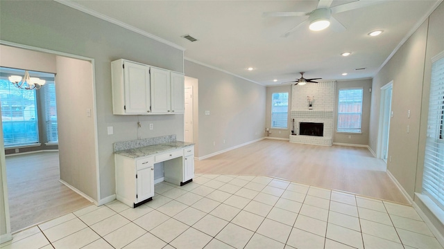 kitchen featuring light tile patterned floors, white cabinetry, light stone counters, ornamental molding, and a brick fireplace