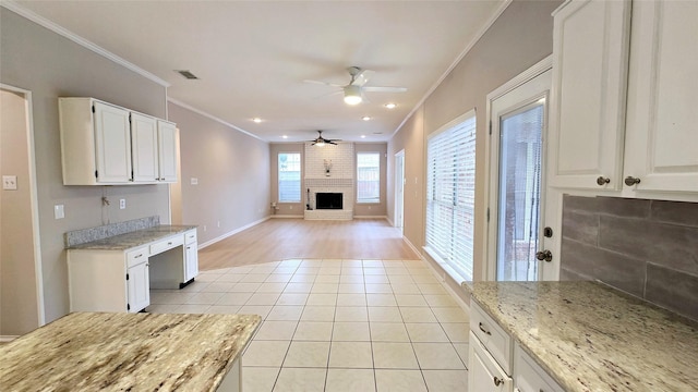 kitchen with ornamental molding, a brick fireplace, light tile patterned floors, and white cabinets