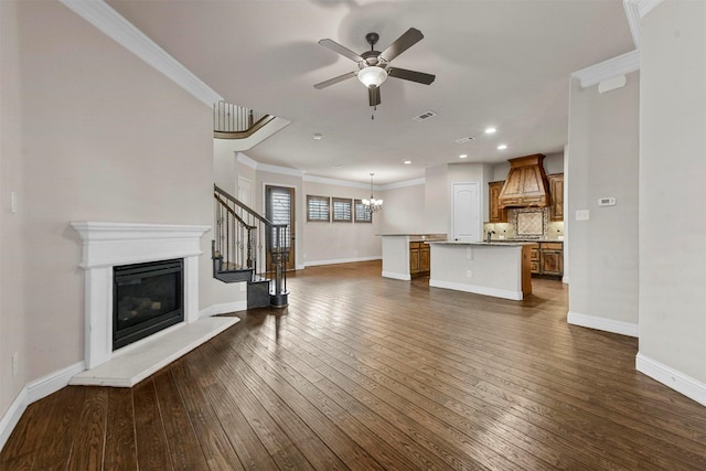 unfurnished living room with dark wood-type flooring, ornamental molding, and ceiling fan with notable chandelier