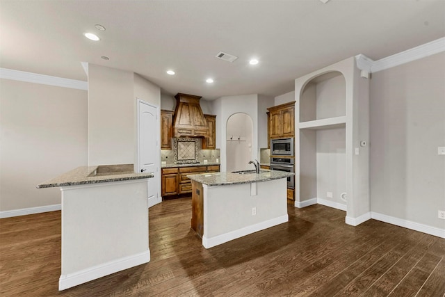 kitchen featuring custom exhaust hood, an island with sink, appliances with stainless steel finishes, and sink