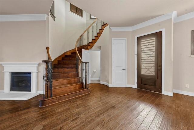 entrance foyer with ornamental molding and dark hardwood / wood-style floors