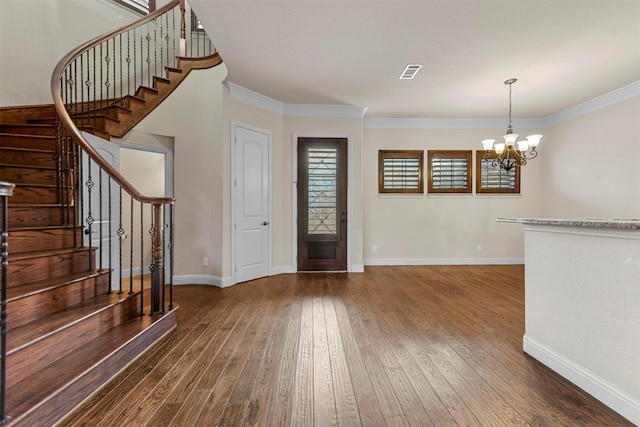 foyer with dark wood-type flooring, ornamental molding, and a notable chandelier