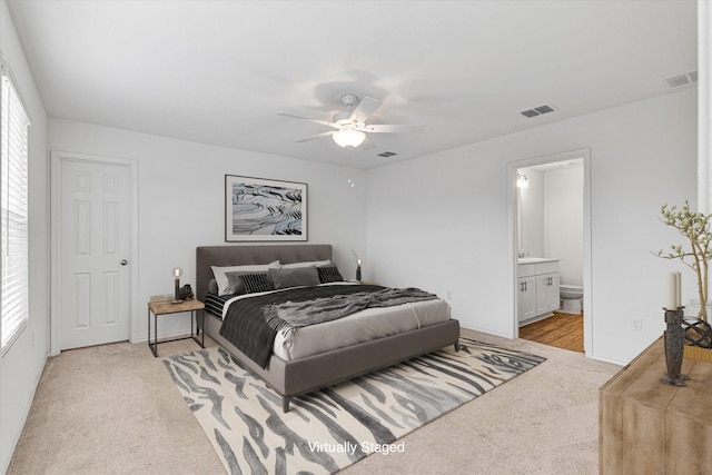 carpeted bedroom featuring multiple windows, ensuite bath, and ceiling fan