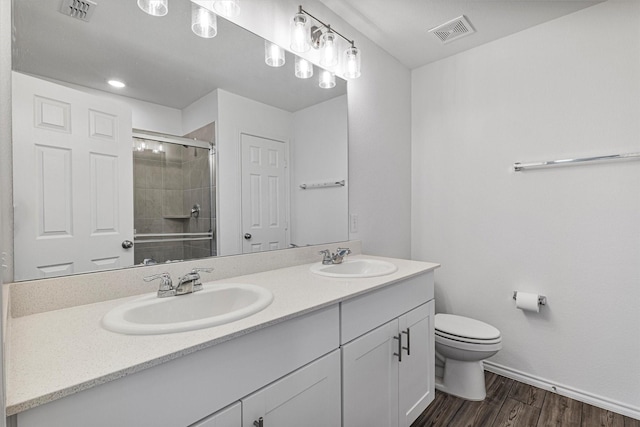 bathroom with hardwood / wood-style floors, vanity, toilet, and a shower with door