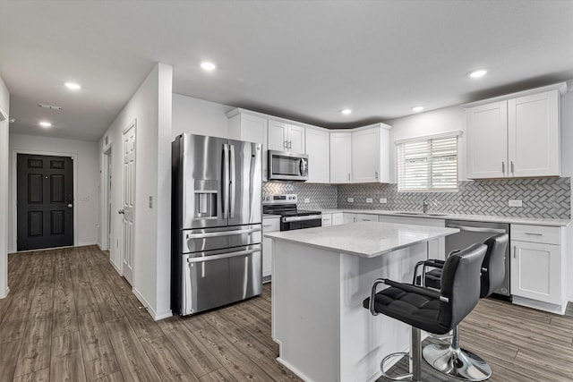 kitchen with white cabinets, a kitchen breakfast bar, sink, a kitchen island, and stainless steel appliances