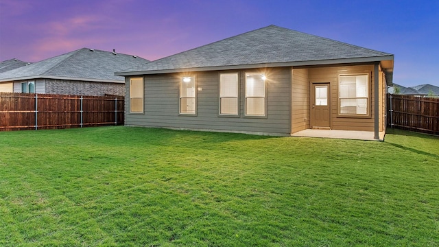 back house at dusk with a lawn