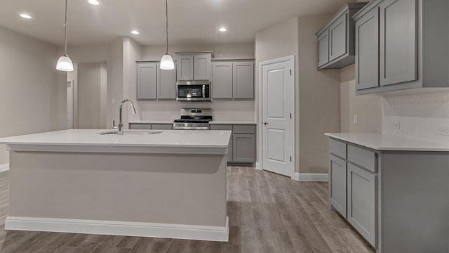 kitchen with stainless steel appliances, decorative light fixtures, gray cabinets, and sink