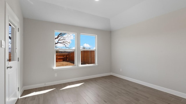 spare room with lofted ceiling and dark hardwood / wood-style flooring