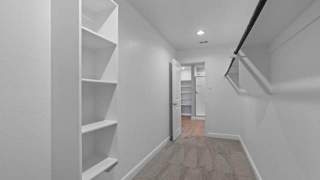 spacious closet featuring light colored carpet