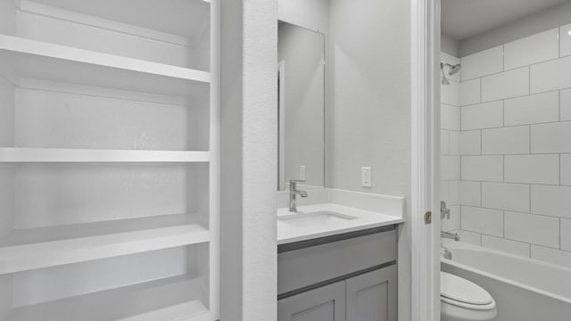 full bathroom featuring vanity, tiled shower / bath, and toilet