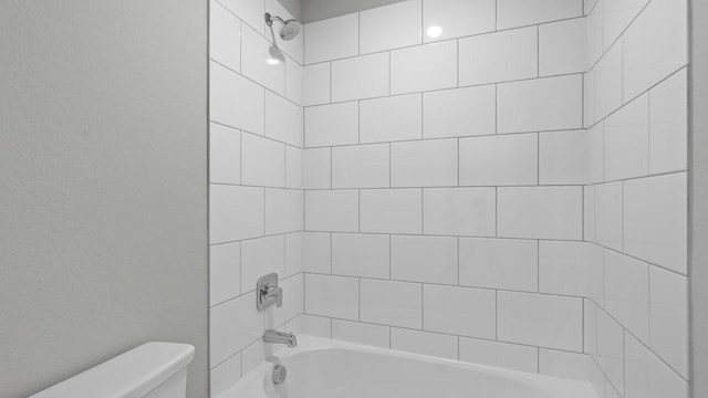 bathroom featuring tiled shower / bath combo and toilet