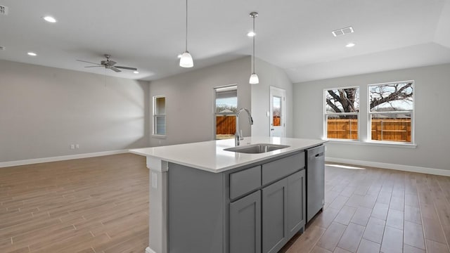 kitchen featuring sink, gray cabinets, dishwasher, hanging light fixtures, and a center island with sink