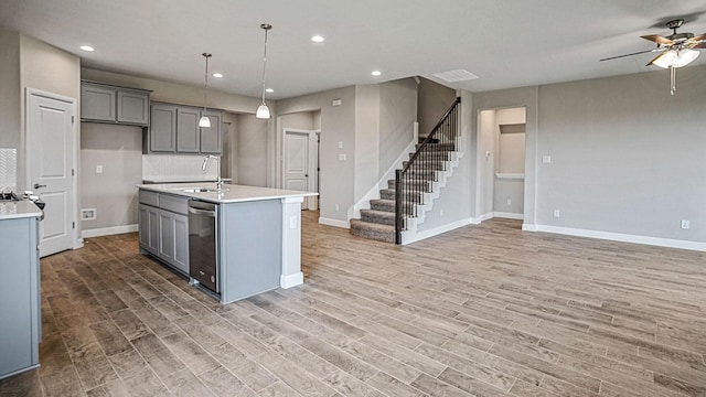 kitchen featuring sink, decorative light fixtures, a center island with sink, dishwasher, and gray cabinets