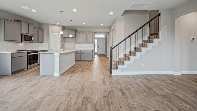 kitchen featuring decorative backsplash, pendant lighting, an island with sink, and stainless steel appliances