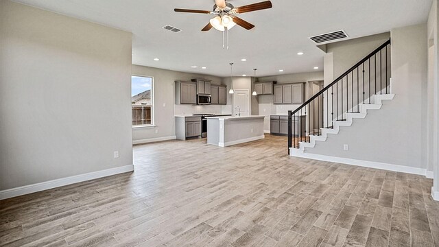 unfurnished living room featuring ceiling fan, sink, and light hardwood / wood-style flooring