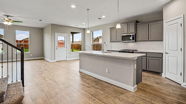 kitchen featuring hardwood / wood-style floors, sink, hanging light fixtures, gray cabinets, and stainless steel appliances