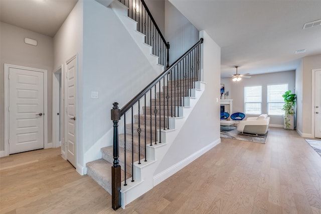 stairs featuring hardwood / wood-style flooring and ceiling fan