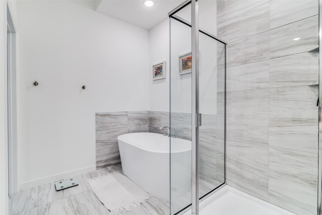 bathroom featuring plus walk in shower and tile walls