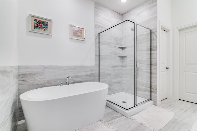 bathroom with tile walls and independent shower and bath