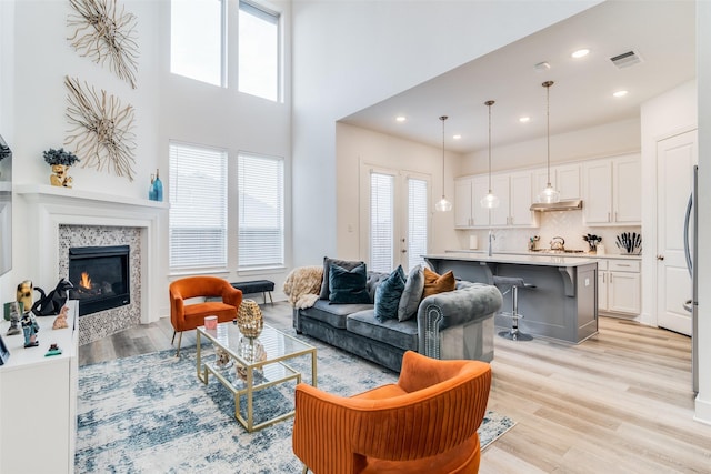 living room with a tile fireplace, a wealth of natural light, sink, and light wood-type flooring