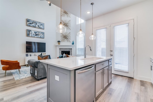 kitchen featuring gray cabinetry, sink, decorative light fixtures, dishwasher, and an island with sink