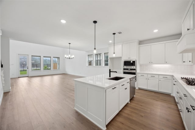 kitchen featuring white cabinetry, appliances with stainless steel finishes, sink, and an island with sink