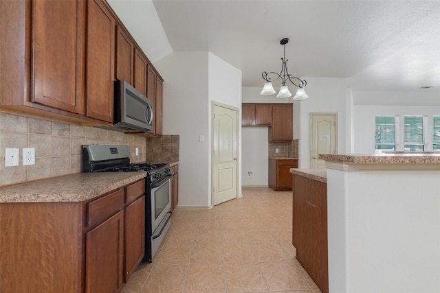 kitchen featuring appliances with stainless steel finishes, pendant lighting, tasteful backsplash, and a notable chandelier