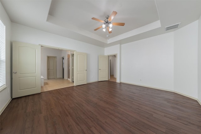 unfurnished room with a tray ceiling, ceiling fan, and light wood-type flooring